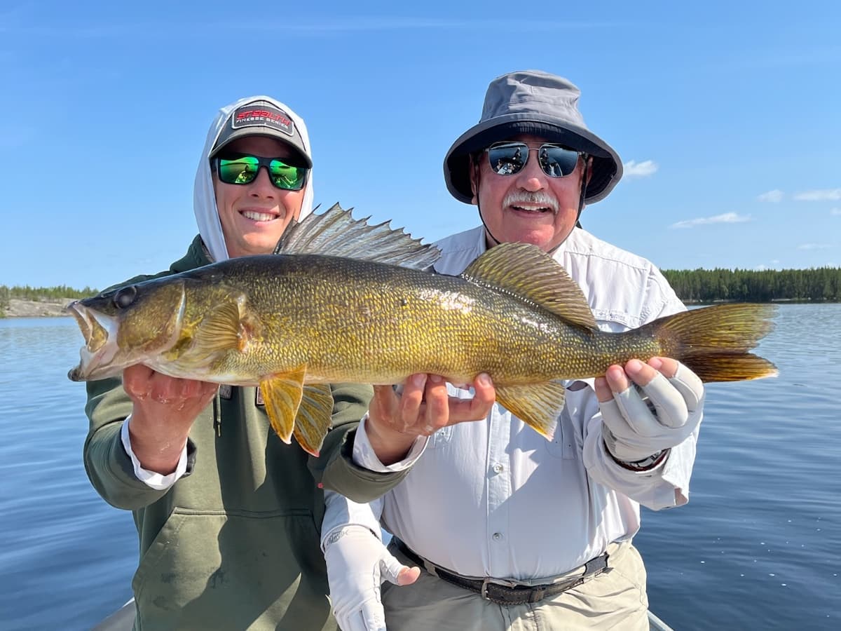 Two smiling guests holding a big golden Dogskin Lake walleye